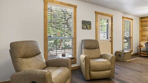 A room with two leather armchairs, large windows with blinds, a door, and a small table. - Big Fern Cabin in Leakey (Leakey)