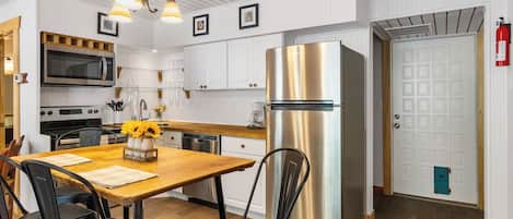 Una cocina moderna con electrodomésticos de acero inoxidable, una mesa de comedor de madera y sillas negras.