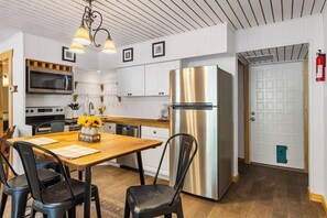 Une cuisine moderne équipée d’appareils électroménagers en acier inoxydable, avec une table à manger en bois et des chaises noires.