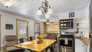 A modern kitchen with stainless steel appliances, a wooden dining table, and a cozy seating area. - Big Fern Cabin in Leakey (Leakey)