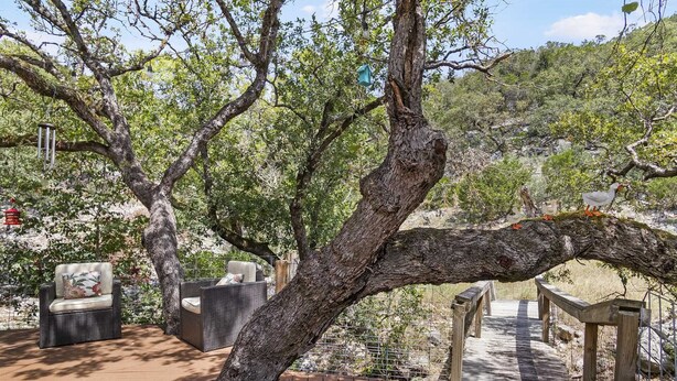 A wooden deck with wicker furniture and a metal railing. - Big Fern Cabin in Leakey (Leakey)