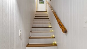 A staircase with wooden steps and a wooden handrail, leading to a door with a small picture on the wall. - Big Fern Cabin in Leakey (Leakey)