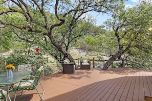 An outdoor patio area with a wooden deck, wicker furniture, and a glass table.