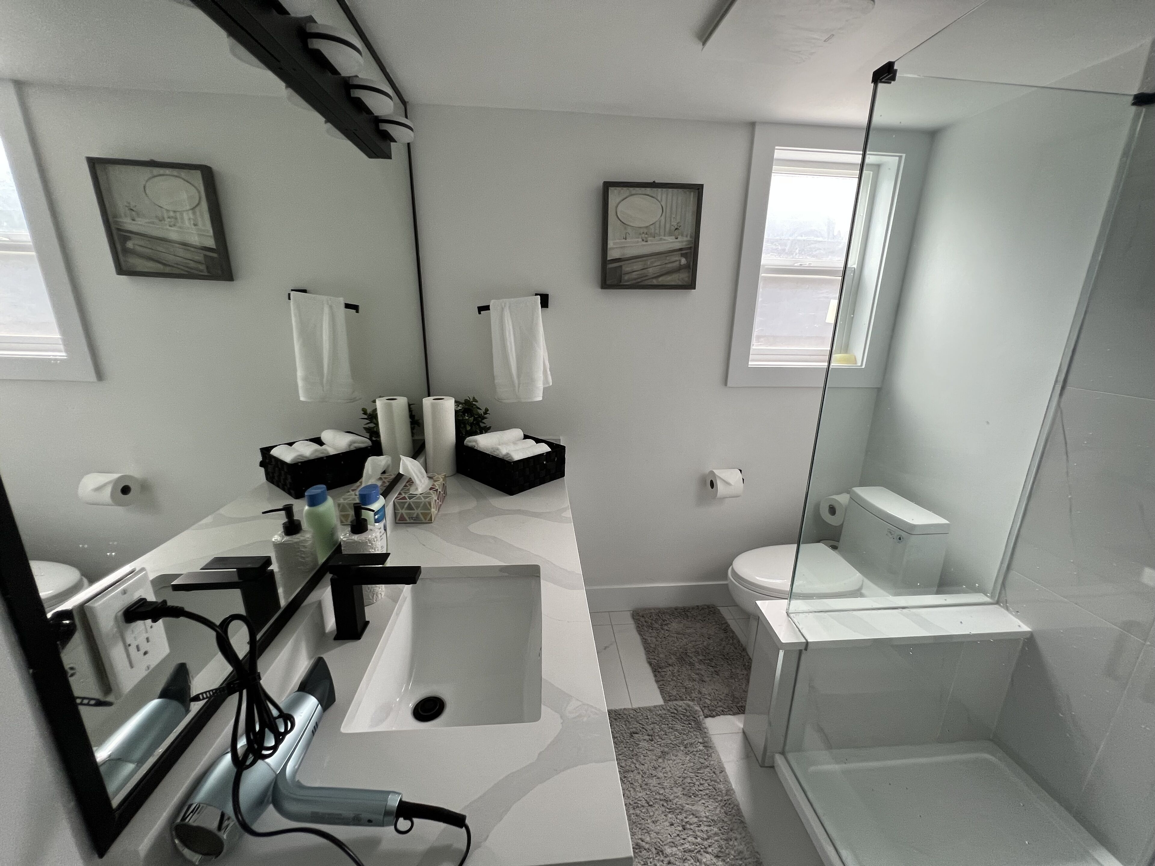 A modern bathroom with a large mirror, a sink, a toilet, and a shower area.