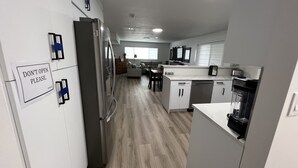 Een moderne keuken met een koelkast, vaatwasser en een bord waarop staat 'OPEN NIET ALSJEBLIEFT'.