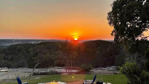 Vista al atardecer desde un patio con dos sillas y una chimenea.