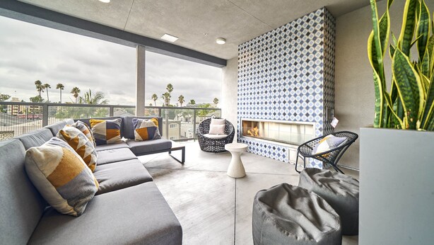 Un espace extérieur moderne aménagé avec un canapé, des fauteuils et une petite table.