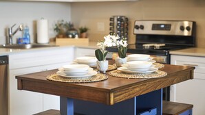 Une cuisine avec des armoires blanches, un four à micro-ondes et une cuisinière. On y trouve des assiettes et un vase avec des fleurs sur le comptoir.