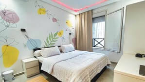 A bedroom with a bed, bedside tables, a desk, and a window with curtains. - Anza Beach View Apartment (Agadir)
