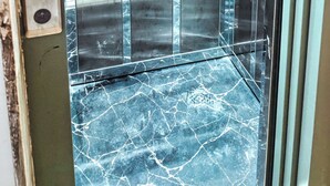 An elevator interior with a digital display, reflective surfaces, and a marble floor. - Anza Beach View Apartment (Agadir)
