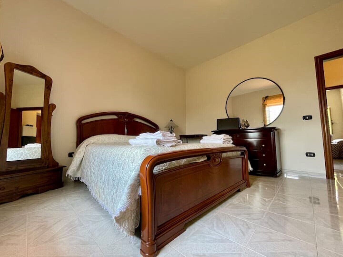 Ein Schlafzimmer mit einem hölzernen Bett, einem Schminktisch, einem Spiegel und einem Fernseher.