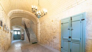 Ein Flur mit Steinwänden, einer Treppe, einem Chandelier und hellblauen Türen.