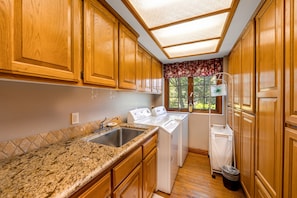 Kitchen area with dishwasher, stainless steel sink, and laundry cart.
