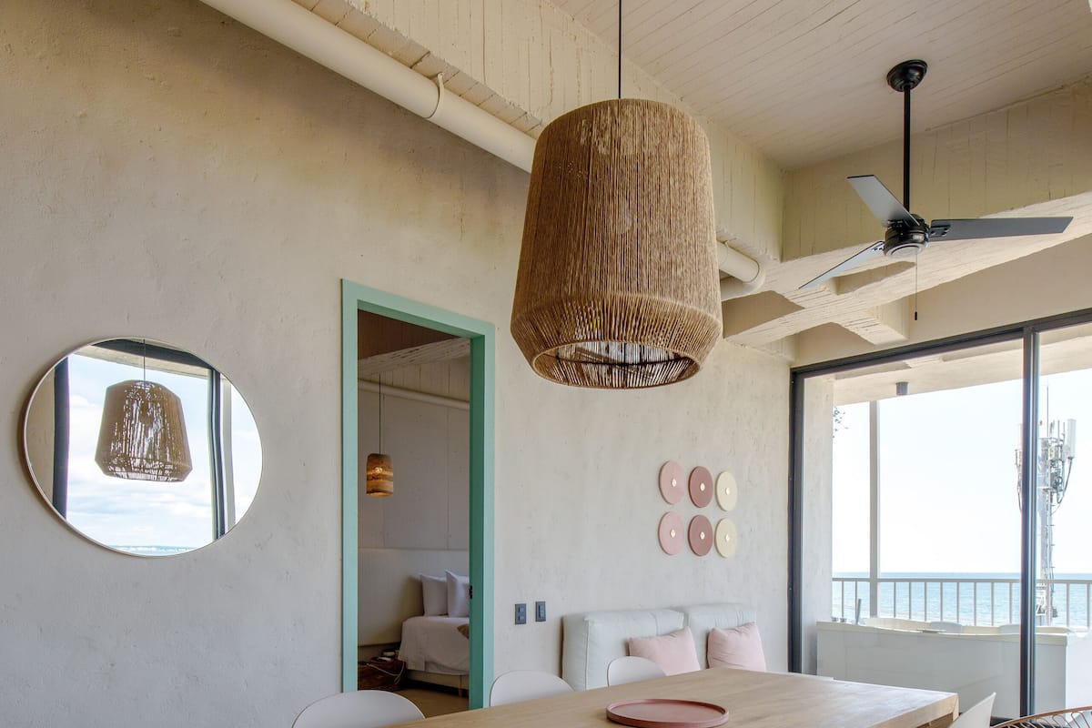 A modern dining area with a wooden table, white chairs, and a hanging light fixture.