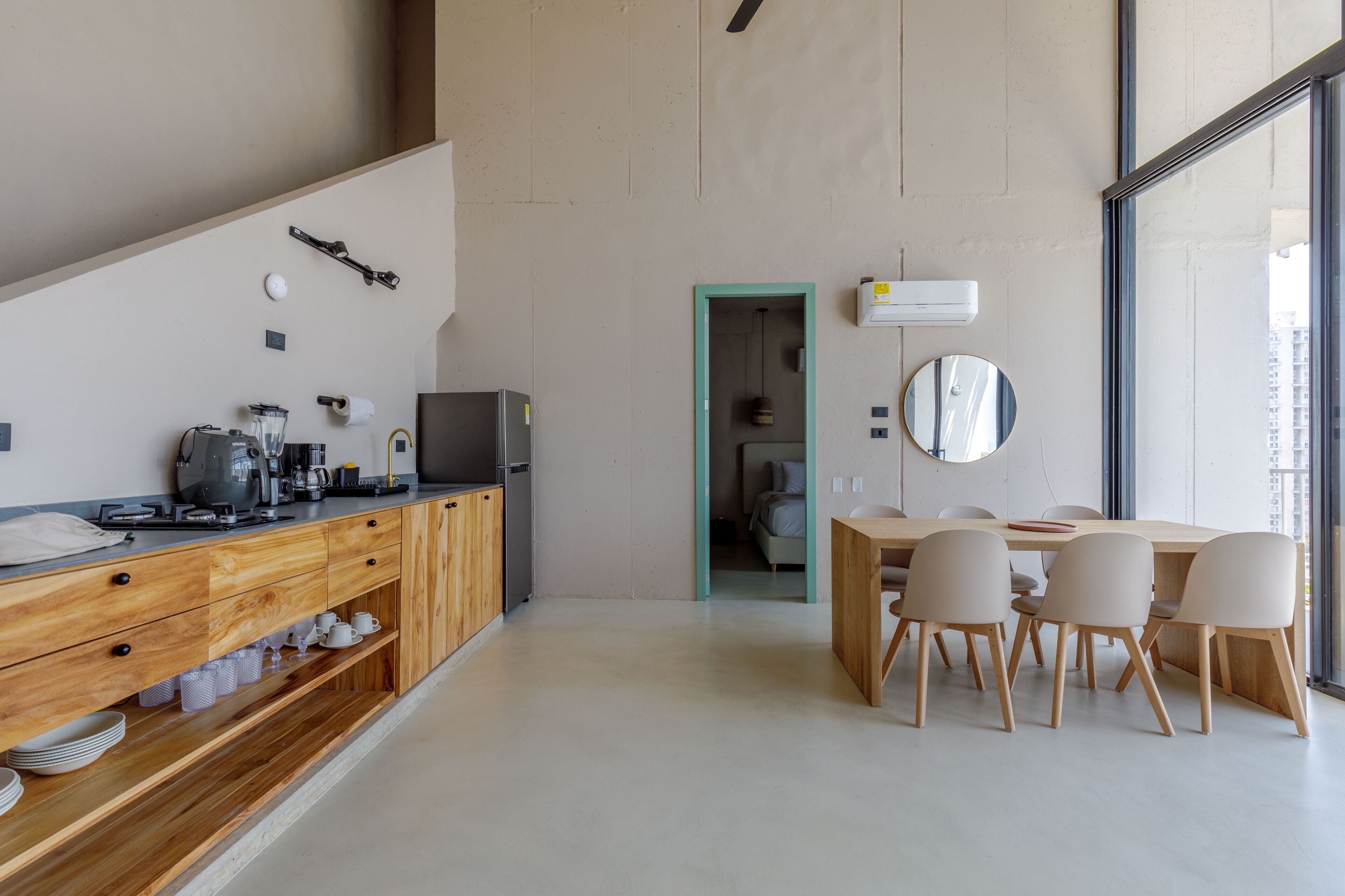 A modern kitchen with wooden cabinets, a coffee machine, and a dining area with a table and chairs.