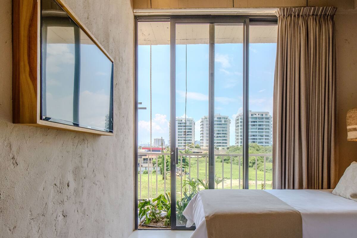 A hotel room with a large window, a ceiling fan, and two beds.