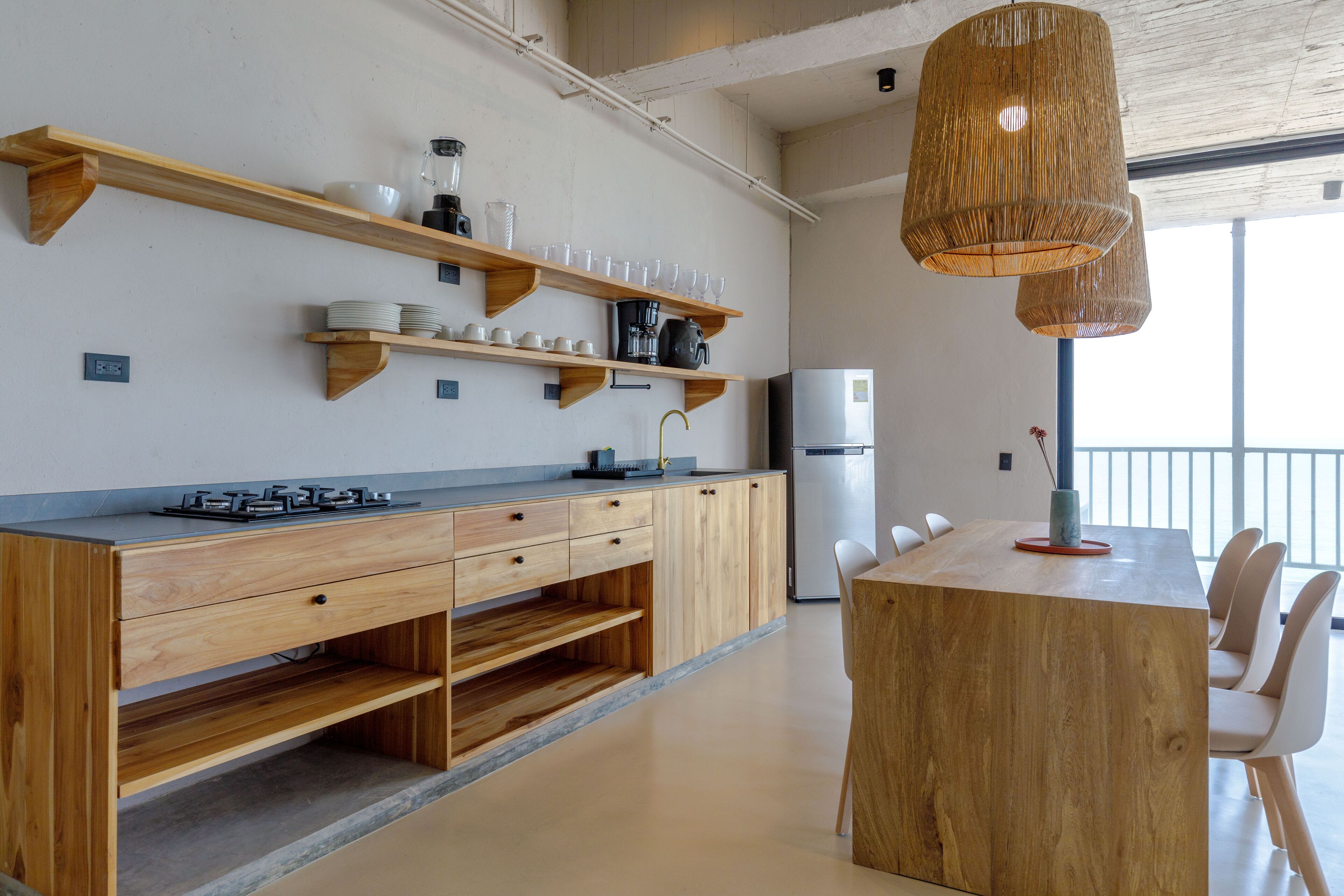 Une cuisine moderne avec des meubles en bois, une cuisinière à gaz intégrée et un coin repas comprenant une table et des chaises en bois.
