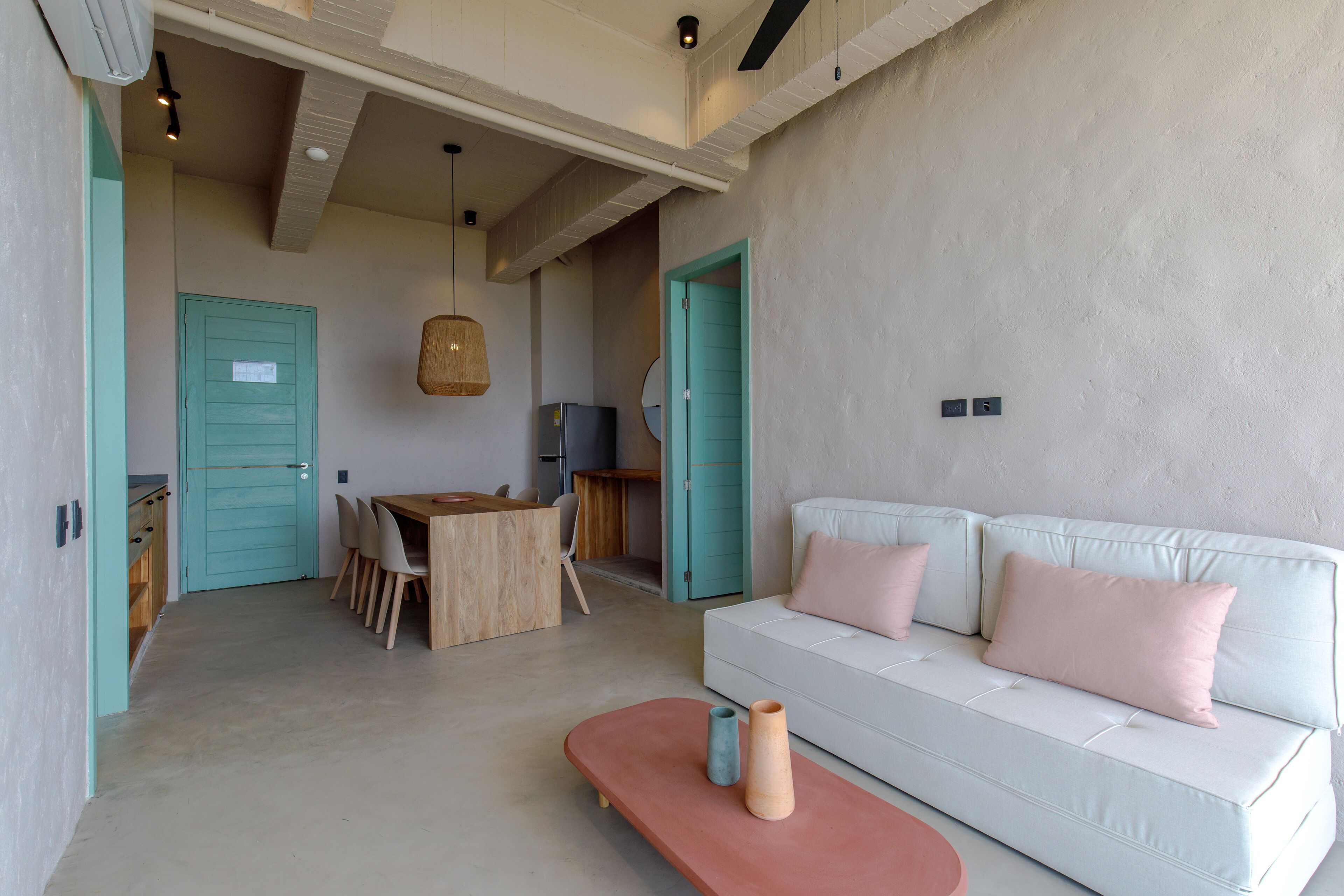Un salon moderne avec un canapé blanc, des portes de couleur turquoise et une table à manger en bois.