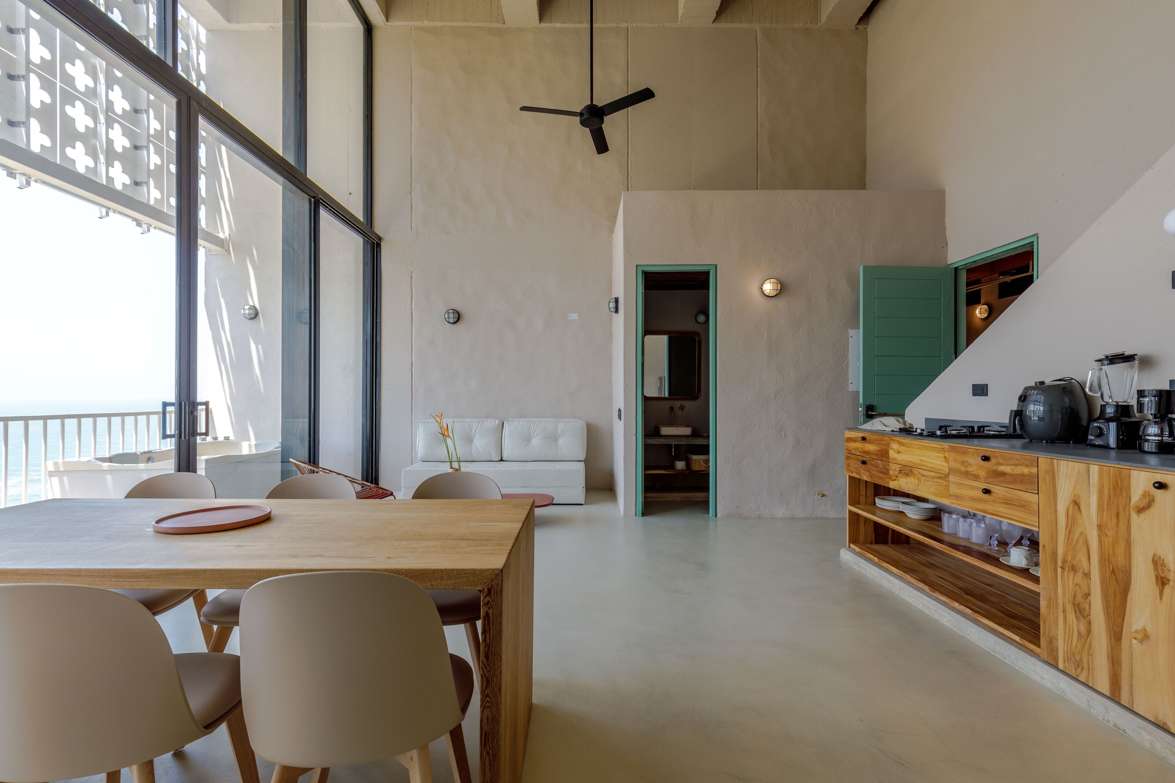 A spacious kitchen with a wooden table and chairs, a built-in oven, and a view of the balcony.