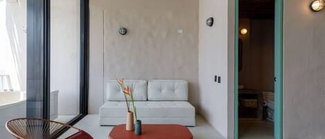 A modern living room with a white sofa, a red coffee table, and a wicker chair.