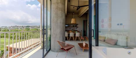 A balcony with a glass door leading to a dining area, a large pillar, and a hot tub.
