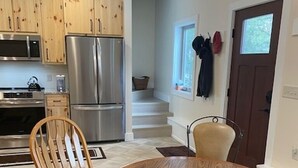 Una cocina moderna con armarios de madera, electrodomésticos de acero inoxidable y una mesa redonda con dos sillas.