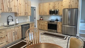 Una cocina moderna con armarios de madera, electrodomésticos de acero inoxidable y una zona de comedor con mesa y sillas.