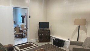 Una sala de estar con sofá, mesa de centro, televisor, lámpara y un mueble bajo.