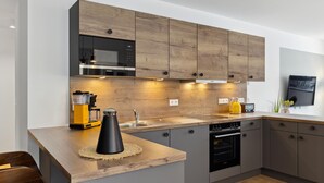 A modern kitchen with wooden cabinets, a built-in microwave, a coffee machine, and a kettle on the counter. - GebirgsResort Winterberg (Winterberg)