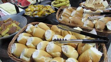A buffet with various food items including bread, fruits, and pastries.