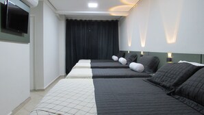 Una habitación de hotel con dos camas, un televisor de pantalla plana y una lámpara en el techo.