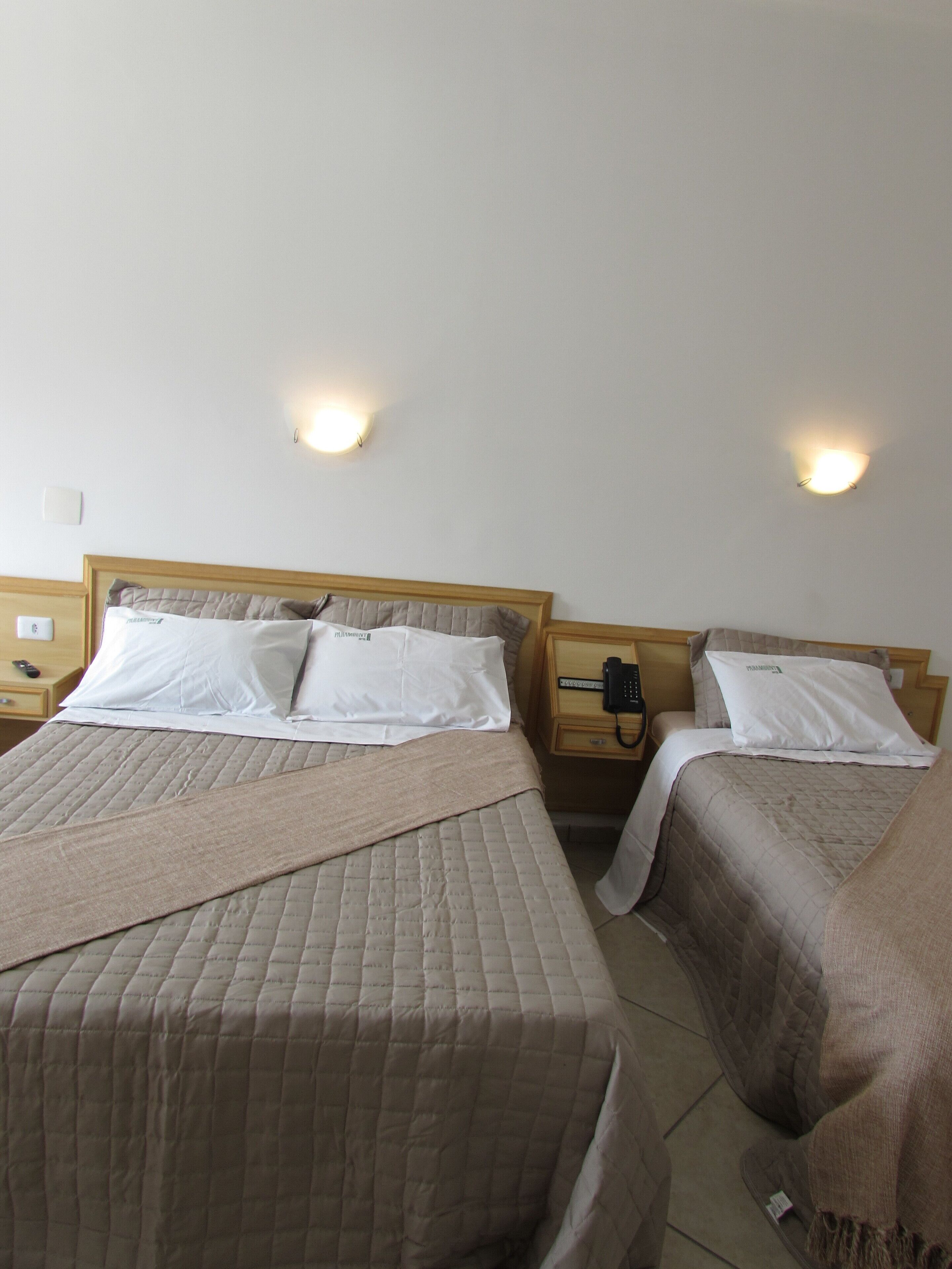 Two twin beds with headboards, bedside tables with lamps, and a wall-mounted light fixture.