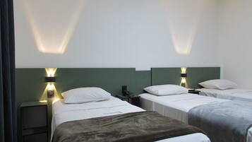 Een hotelkamer met twee eenpersoonsbedden, een nachtkastje met telefoon en wandlampen.