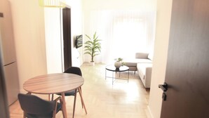 A modern living room with a sofa, a round dining table with chairs, a small coffee table, and a potted plant. - Citybreak Apartments 301 in Athens, Greece (Athens)