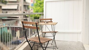 A balcony with a wooden table and chairs, a potted plant, and a white wall. - Citybreak Apartments 301 in Athens, Greece (Athens)