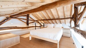 Un dormitorio con techo de madera, una cama, un escritorio y un ventanal.