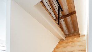 Una escalera de madera con paredes blancas y barandilla de metal.