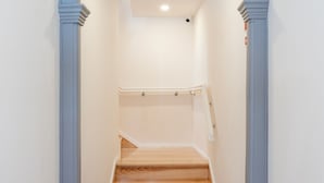 Un couloir étroit avec un escalier en bois et une arche bleue.