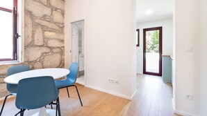 Une pièce avec un mur en pierre, une porte blanche, une table ronde entourée de chaises bleues et un plancher en bois.