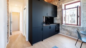 Una cocina moderna con armarios negros, horno integrado y ventana con vistas a edificios.