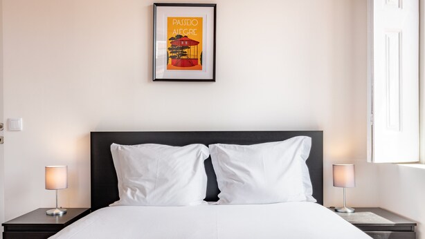 A neatly made bed with white linens, two bedside tables with lamps, and a framed picture on the wall. - VIVA Serralves Vintage House 3 (Porto)