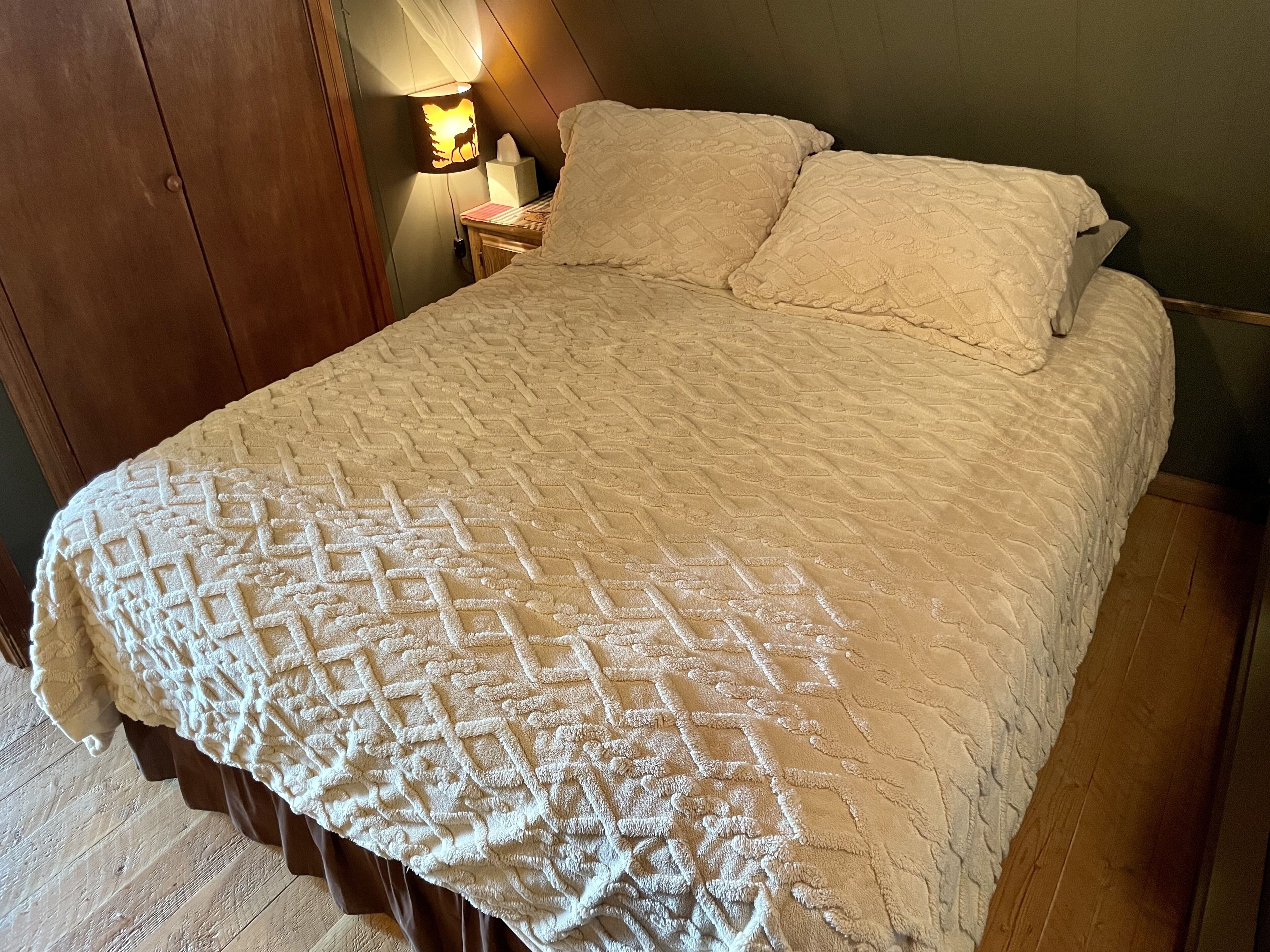 A bed with a quilted blanket, a bedside lamp, and a wooden nightstand.