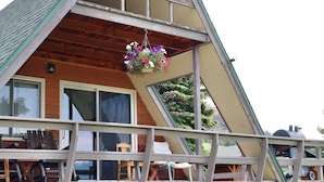 A cabin with a balcony, wooden deck, and a hanging flower basket. - Moose Cabin - Mountain Views, Hear Rushing River, Private, Pet Friendly (Fishtail)