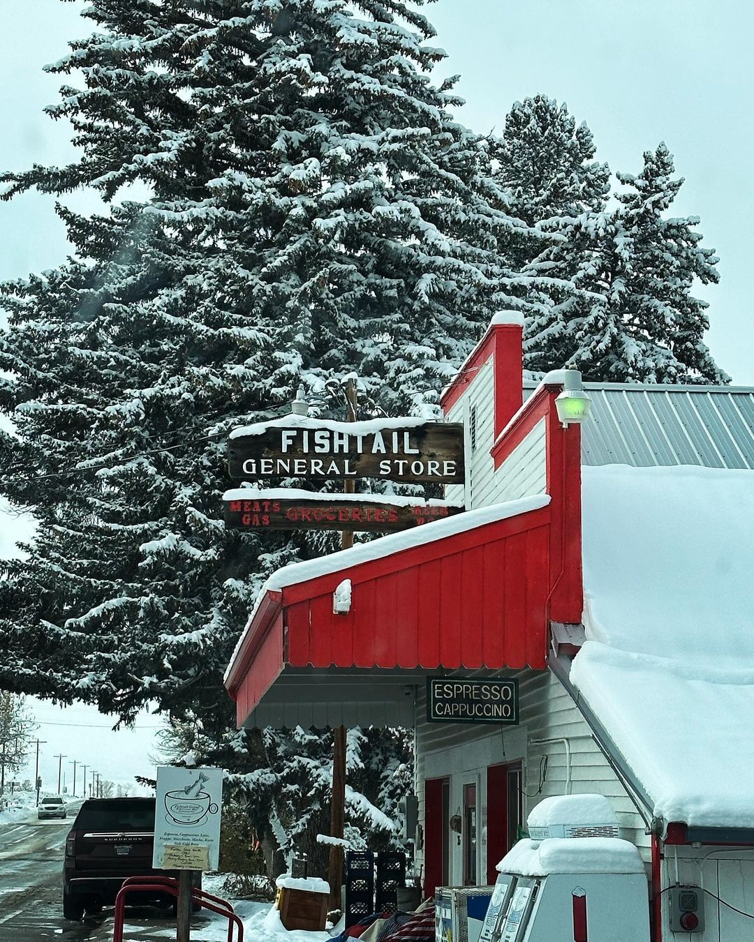 Een winkel met een gevel in rood en wit, omringd door met sneeuw bedekte bomen.