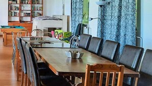 A dining area with a long wooden table, black leather chairs, and a bookshelf in the background. - 4 bedroom beautiful home in Suleczyno (Suleczyno)