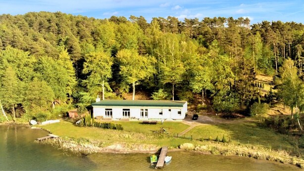 A lakeside property with a white building, dock, and surrounding forest. - 4 bedroom beautiful home in Suleczyno (Suleczyno)