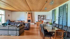 A spacious living area with a wooden ceiling, a fireplace, a sofa set, a dining table with chairs, and a bookshelf. - 4 bedroom beautiful home in Suleczyno (Suleczyno)