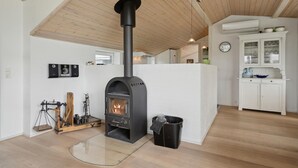 A modern kitchen with a wood-burning stove, white cabinetry, and a wooden ceiling. - Stunning home in Broager with WiFi (Broager)