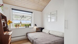 A bedroom with a bed, a wooden desk, a window with a view, and a wall-mounted lamp. - Stunning home in Broager with WiFi (Broager)