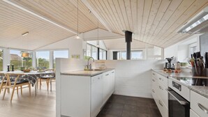 A modern kitchen with white cabinetry, a central island, and a dining area with natural light. - Stunning home in Broager with WiFi (Broager)